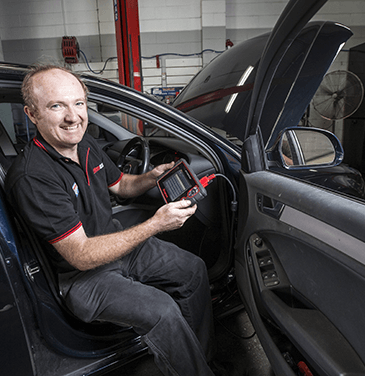 mechanic using diagnostic scan tool in car